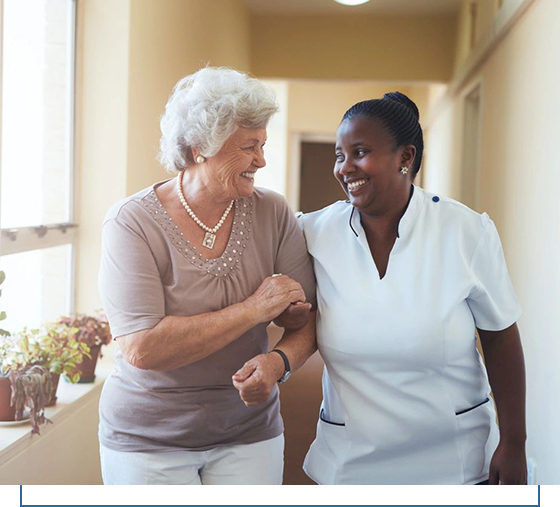 A nurse and an older woman are smiling together.